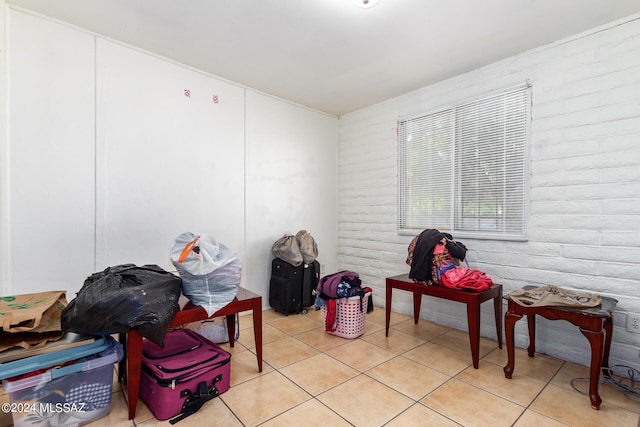 misc room with light tile patterned flooring and brick wall