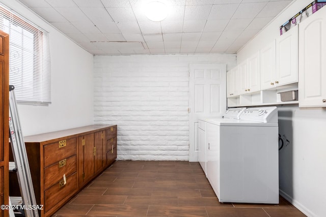 laundry room featuring cabinets, brick wall, and washing machine and dryer