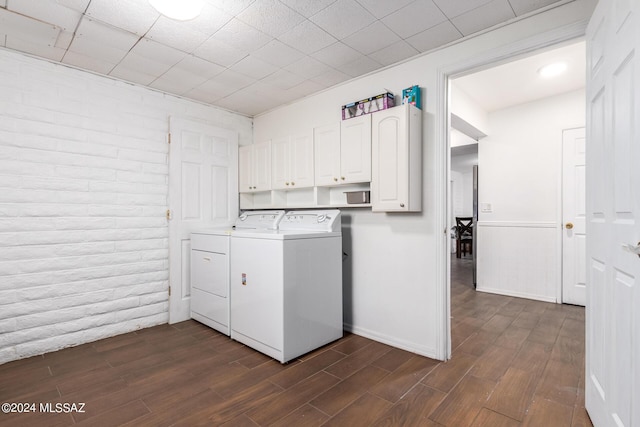 washroom featuring cabinets, dark hardwood / wood-style floors, independent washer and dryer, and brick wall