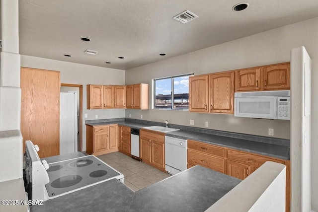 kitchen featuring light tile patterned floors, white appliances, and sink