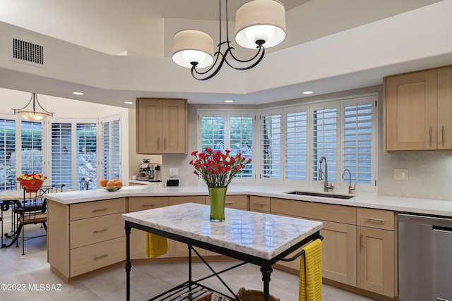 kitchen with pendant lighting, stainless steel dishwasher, light brown cabinetry, and sink