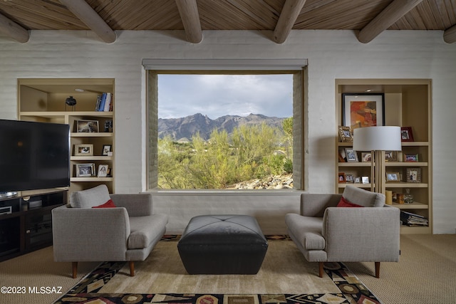 living area with beam ceiling, a mountain view, wood ceiling, and a healthy amount of sunlight