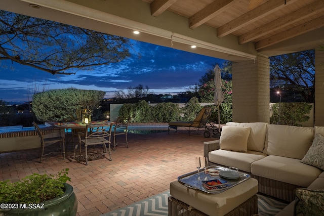 patio terrace at dusk featuring a swimming pool and an outdoor hangout area