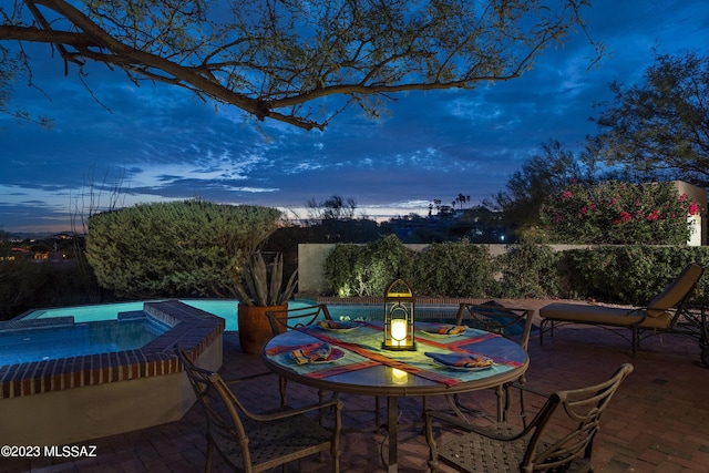 patio terrace at dusk featuring an in ground hot tub