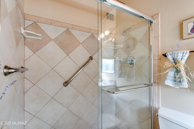 bathroom with toilet and a shower with shower door