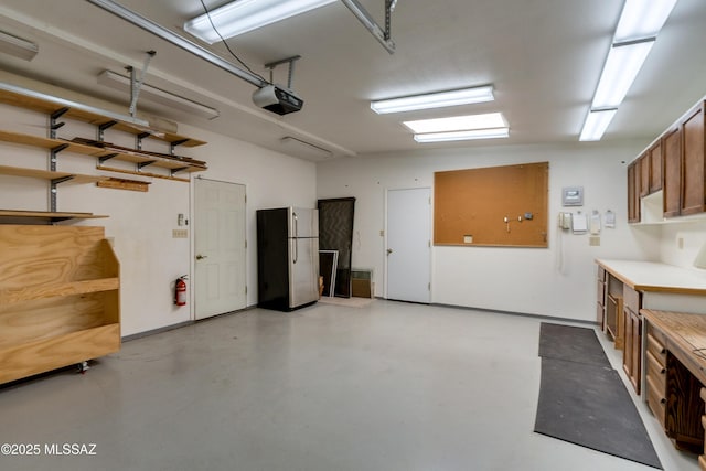 garage featuring a garage door opener, stainless steel fridge, and a workshop area