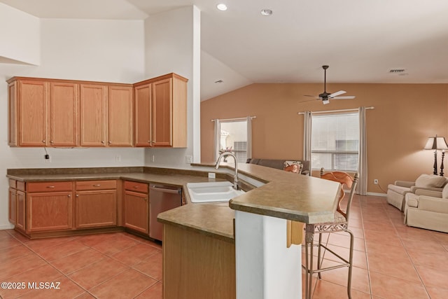 kitchen featuring a breakfast bar area, ceiling fan, light tile patterned flooring, stainless steel dishwasher, and sink