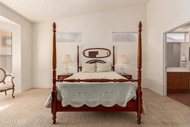 bedroom featuring vaulted ceiling, light carpet, and ensuite bath