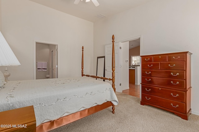 carpeted bedroom with vaulted ceiling, ceiling fan, and ensuite bath