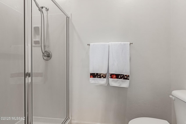 bathroom featuring toilet and a shower with shower door