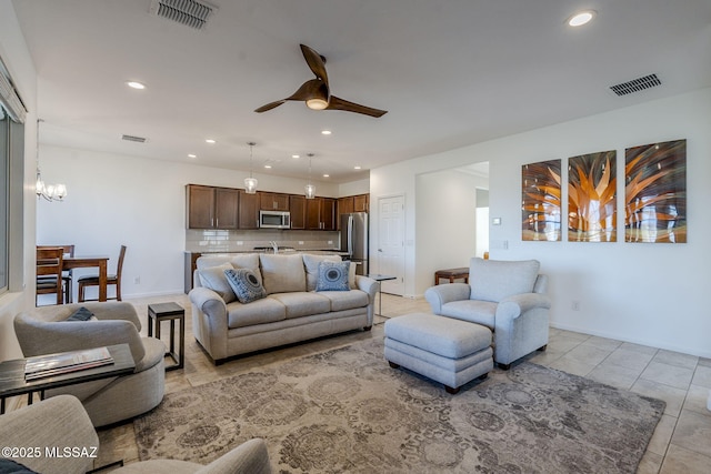 living room featuring ceiling fan with notable chandelier and light tile patterned flooring