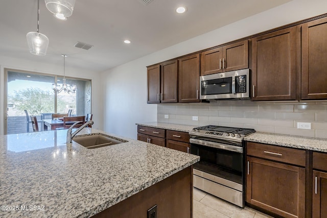 kitchen featuring sink, hanging light fixtures, light stone counters, and appliances with stainless steel finishes