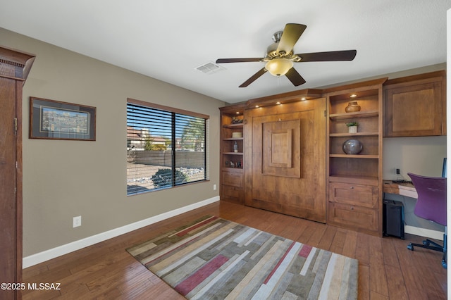 office space featuring dark hardwood / wood-style floors, built in desk, and ceiling fan