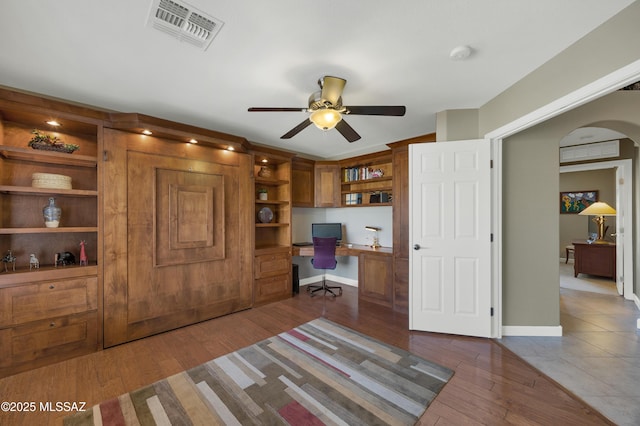 office with ceiling fan, dark hardwood / wood-style floors, and built in desk