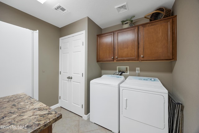 clothes washing area featuring cabinets, light tile patterned flooring, and independent washer and dryer