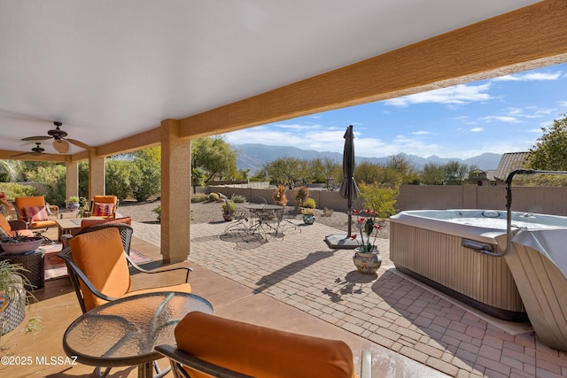 view of patio with a mountain view, a hot tub, and ceiling fan