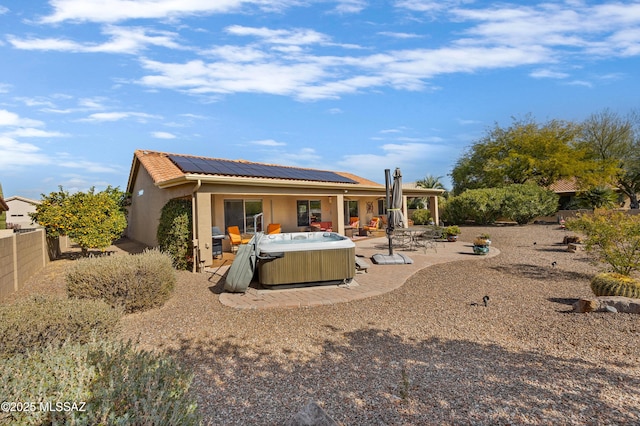 rear view of house featuring a hot tub, a patio area, and solar panels