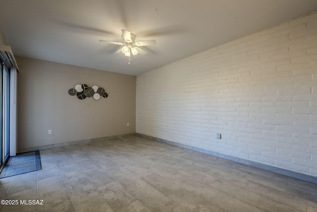 spare room featuring ceiling fan and brick wall