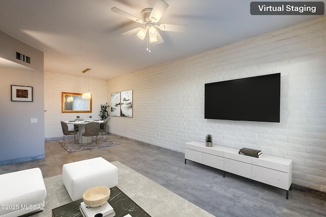 living room featuring ceiling fan and brick wall