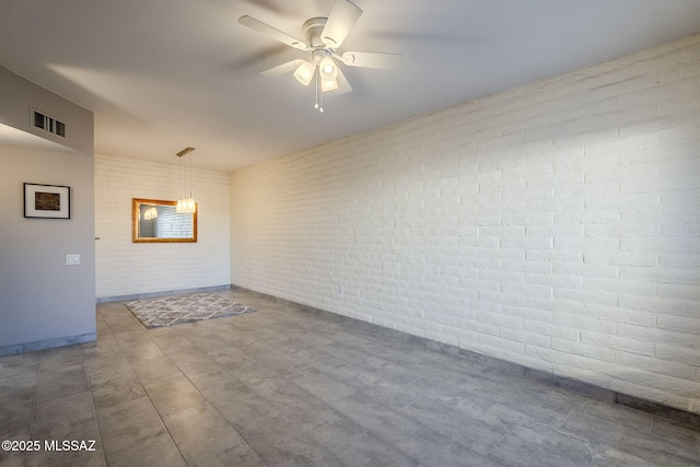 empty room with ceiling fan and brick wall