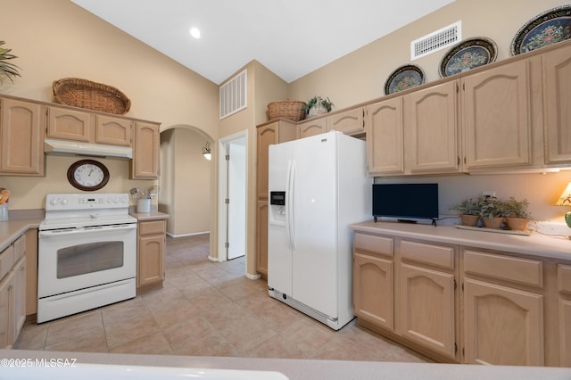 kitchen with light tile patterned floors, white appliances, light brown cabinets, and lofted ceiling