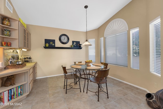 tiled dining room featuring vaulted ceiling