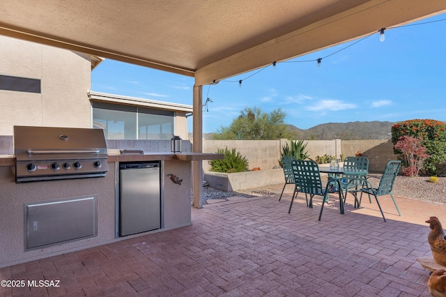 view of patio / terrace with a grill, a mountain view, and exterior kitchen