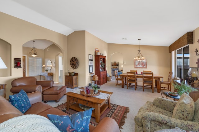 carpeted living room featuring a chandelier and vaulted ceiling