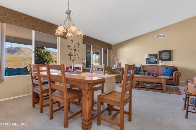 dining area with a mountain view, vaulted ceiling, light carpet, and an inviting chandelier