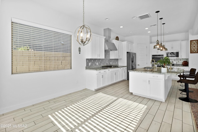 kitchen with decorative backsplash, a kitchen island with sink, hanging light fixtures, and stainless steel appliances