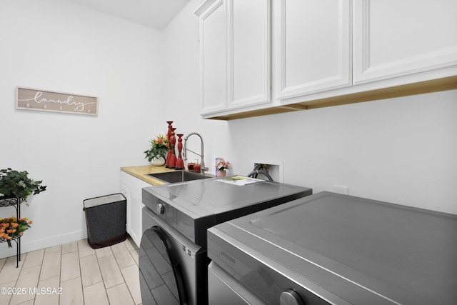 clothes washing area featuring separate washer and dryer, sink, and cabinets