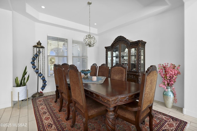 dining space featuring a tray ceiling, light tile patterned flooring, and an inviting chandelier