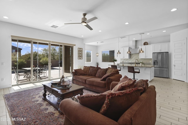 living room with light hardwood / wood-style flooring, ceiling fan, and sink