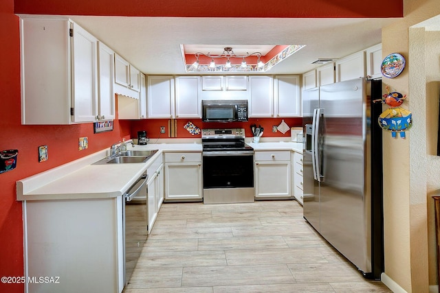 kitchen with stainless steel appliances, white cabinets, a tray ceiling, and sink