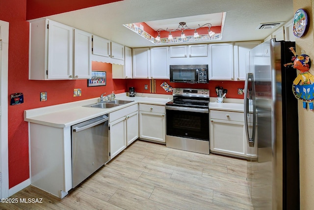 kitchen with sink, white cabinets, appliances with stainless steel finishes, and a raised ceiling