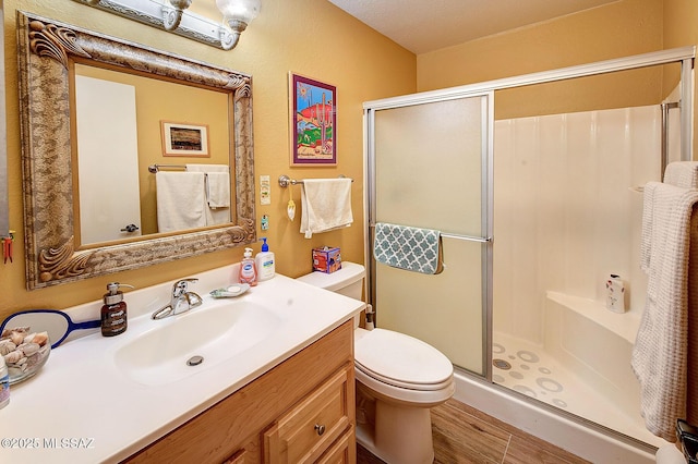 bathroom featuring toilet, hardwood / wood-style flooring, walk in shower, a textured ceiling, and vanity