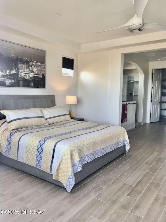 bedroom featuring wood tiled floor, visible vents, and arched walkways