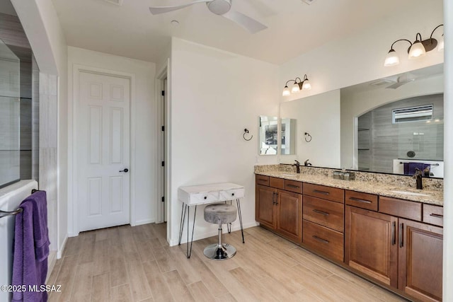 bathroom with a ceiling fan, double vanity, a sink, and wood finished floors