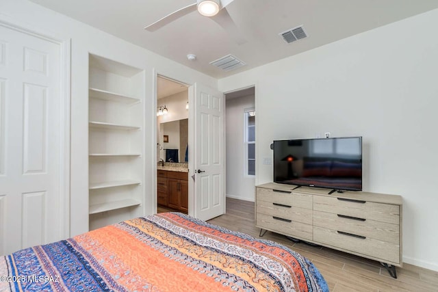 bedroom with wood finish floors, visible vents, a ceiling fan, ensuite bath, and baseboards