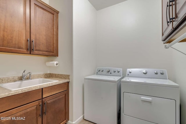 washroom featuring cabinet space, separate washer and dryer, and a sink