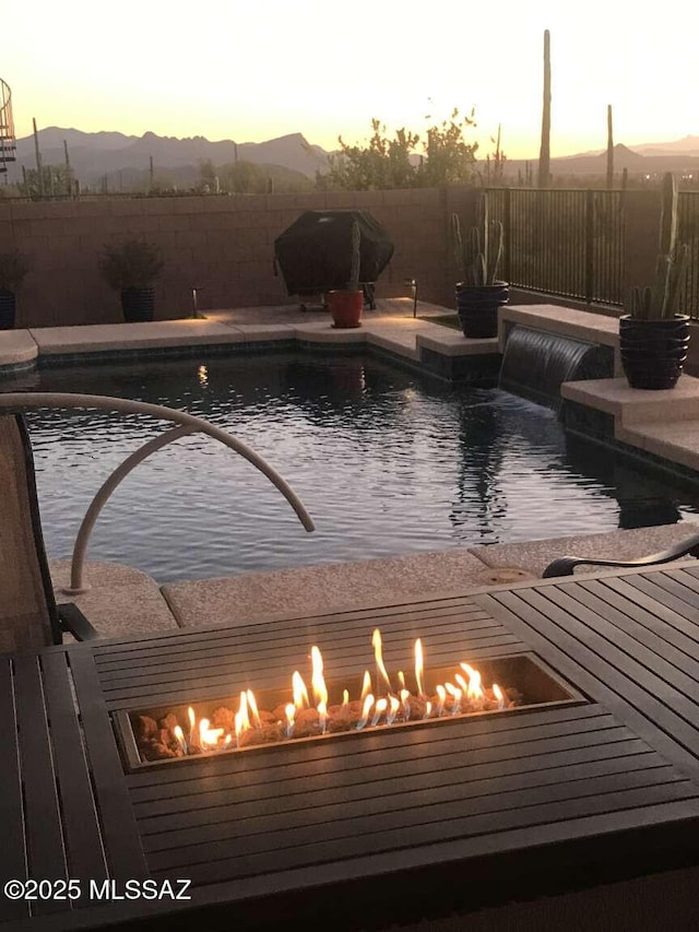 view of pool featuring a fenced in pool, an outdoor fire pit, fence, and a mountain view