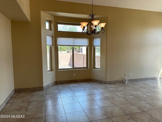 tiled empty room featuring plenty of natural light and an inviting chandelier