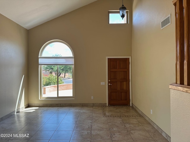 entryway with light tile patterned floors and high vaulted ceiling