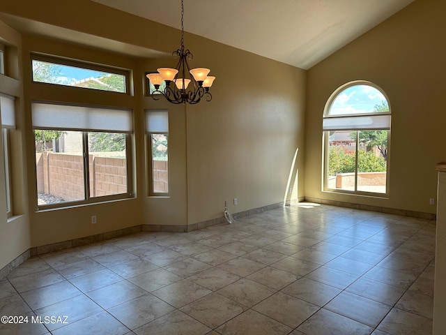 tiled spare room with high vaulted ceiling and a chandelier