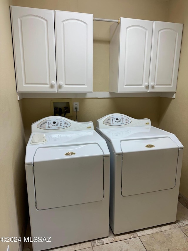 laundry area with light tile patterned flooring, cabinets, and washing machine and dryer