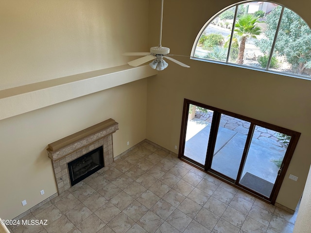 unfurnished living room featuring ceiling fan, light tile patterned floors, and a fireplace