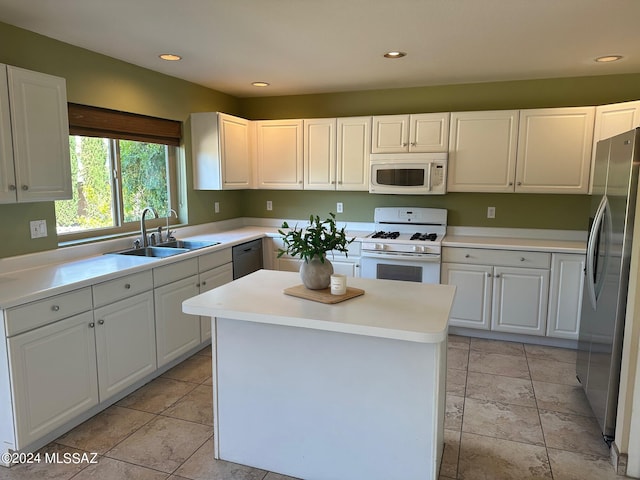 kitchen featuring sink, light tile patterned floors, appliances with stainless steel finishes, a kitchen island, and white cabinetry