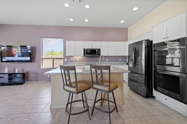 kitchen with a breakfast bar, white cabinetry, appliances with stainless steel finishes, and a center island with sink