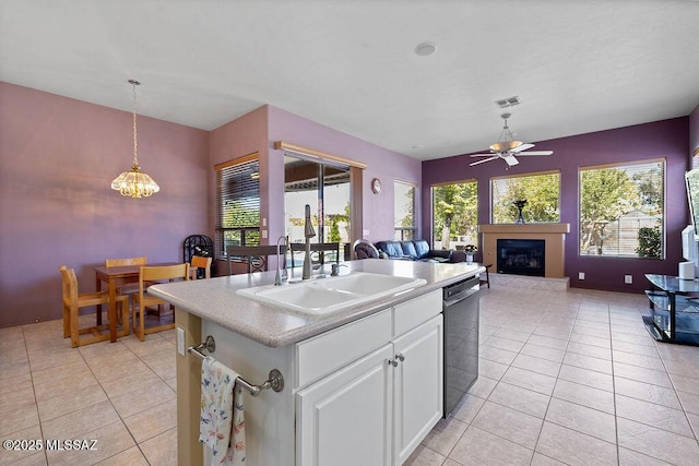 kitchen with dishwasher, white cabinetry, a kitchen island with sink, light tile patterned floors, and sink