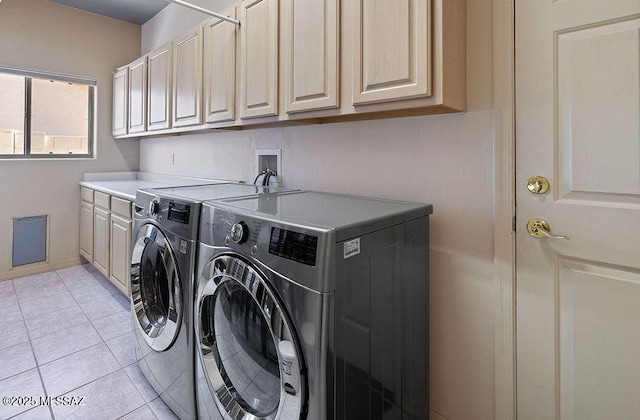 laundry room with light tile patterned floors, cabinets, and washer and dryer